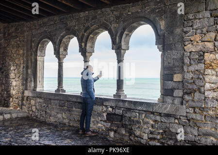 L'uomo maschio turistica prendendo immagini con un telefono dalla loggia di San Pietro, Portovenere e le Cinque Terre, Liguria, Italia Foto Stock