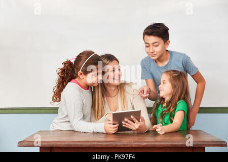 Bambini e insegnanti che lavorano insieme su tablet computer in computer science lezioni Foto Stock