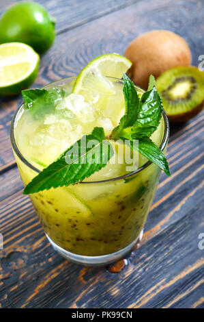 Cocktail di vitamine in un bicchiere su un tavolo di legno. Mojito da kiwi, calce, menta, ghiaccio. Close-up. Foto Stock