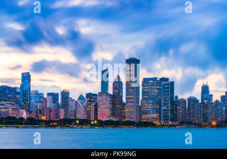 Sullo skyline di Chicago al tramonto con il cielo nuvoloso e riflesso nell'acqua. Foto Stock