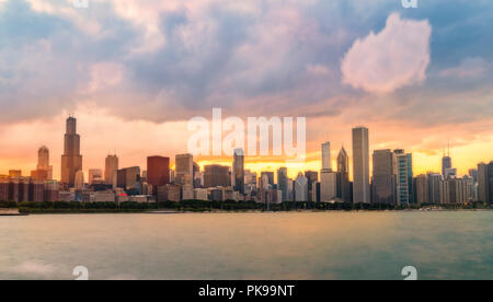 Sullo skyline di Chicago al tramonto con il cielo nuvoloso e riflesso nell'acqua. Foto Stock