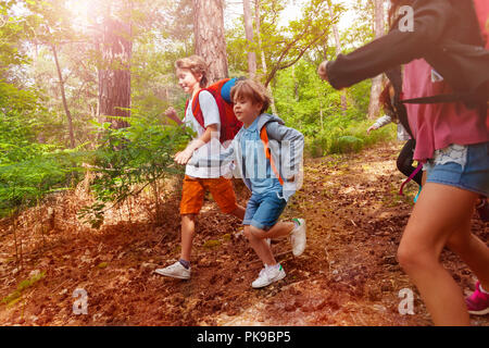 Due ragazzi corrono in foresta tenendo le mani Foto Stock