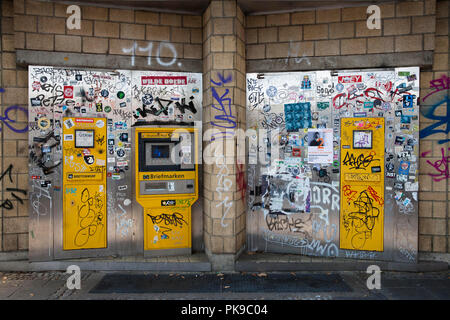 Incollate e cosparse le cassette postali e timbro automat presso un ufficio postale nel quartiere Ehrenfeld, Colonia, Germania. beklebte und beschmierte Briefkaesten Foto Stock