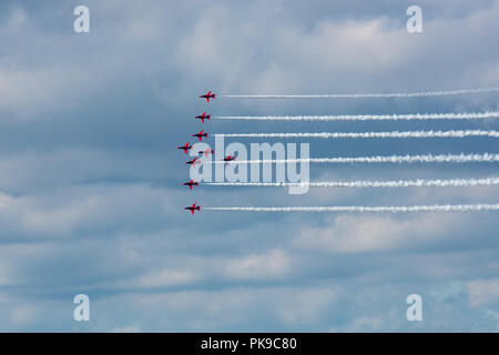 La RAF Rosso di frecce team display in "fulmine" formazione contro un cielo pesante. Foto Stock