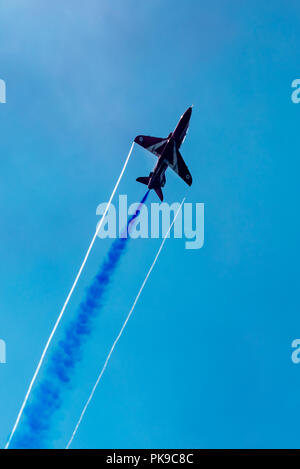 Contrasto Punta Ala e fumo blu percorsi da un BAe Hawk della RAF Rosso di frecce acrobazia team display Foto Stock