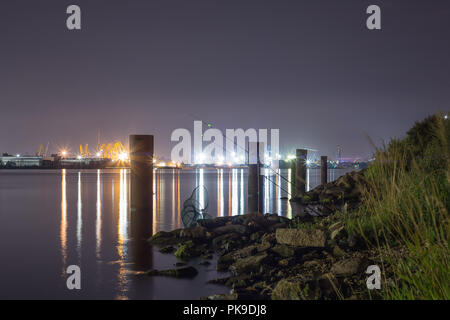La pesca nella notte estiva accanto al terminal di container nel porto di Riga, scena notturna sfondo Foto Stock