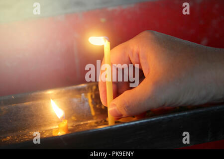 Buddisti di rendere merito,posizionando una candela accesa e incenso illuminato con candele telaio sull altare del Buddha a tempio. Messa a fuoco selettiva. Foto Stock