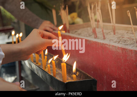 Buddisti di rendere merito,posizionando una candela accesa e incenso illuminato con candele telaio sull altare del Buddha a tempio. Messa a fuoco selettiva. Foto Stock