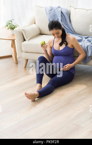 Allegra donna incinta tenendo un Apple Foto Stock