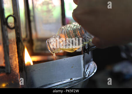 Buddisti di rendere merito,l'olio riempire in una lampada per l'illuminazione e per l'uso nell'incenso. Mezzi per rendere la vita senza intoppi. Messa a fuoco selettiva. Foto Stock