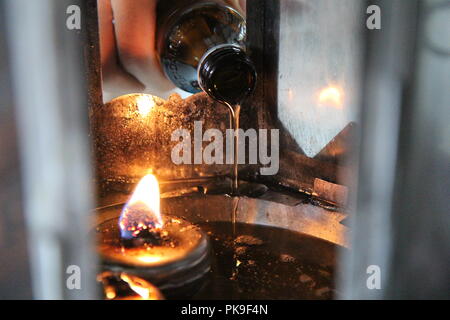 Buddisti di rendere merito,l'olio riempire in una lampada per l'illuminazione e per l'uso nell'incenso. Mezzi per rendere la vita senza intoppi. Messa a fuoco selettiva. Foto Stock