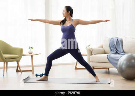 Allegra donna incinta a praticare yoga a casa Foto Stock