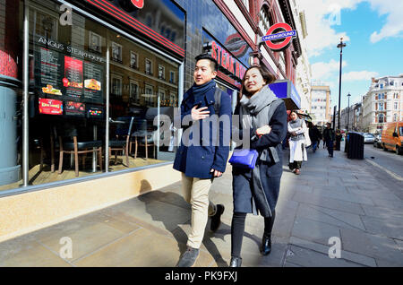 Giovani cinesi giovane passando la stazione della metropolitana di Leicester Square. Londra, Inghilterra, Regno Unito. Foto Stock