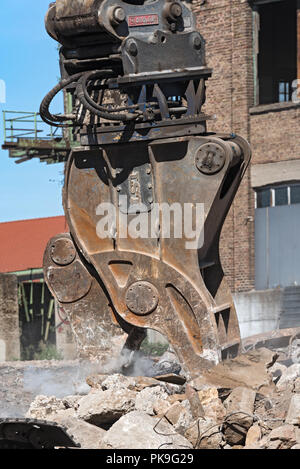 Demolizione la benna mordente di un escavatore in un cantiere durante i lavori di demolizione. Foto Stock