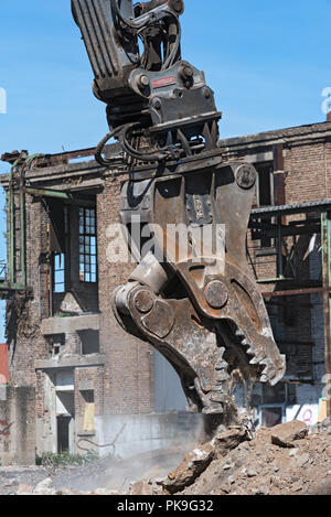 Demolizione la benna mordente di un escavatore in un cantiere durante i lavori di demolizione. Foto Stock