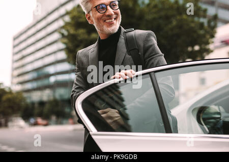 Felice coppia commuter arrivare al di fuori di un taxi. Imprenditore scendere una cabina. Foto Stock