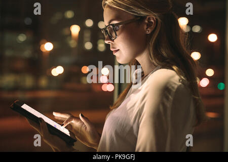 Close up della donna che indossa gli occhiali in piedi in ufficio utilizzando computer tablet. Business donna che utilizza un computer tablet sul lavoro. Foto Stock