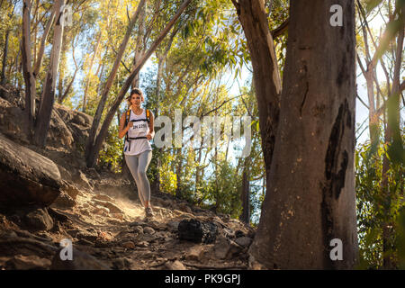 Sani di sesso femminile in runner correndo giù per la collina con alberi in background. Montare trail runner in mountain trail marathon. Foto Stock