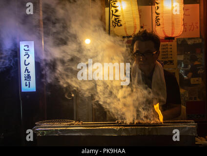 Fornitore preparare del cibo su barbecue grill a street market, regione di Kanto, Tokyo, Giappone Foto Stock