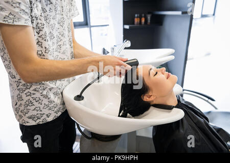 Bella bruna lava i capelli in un salone di bellezza Foto Stock