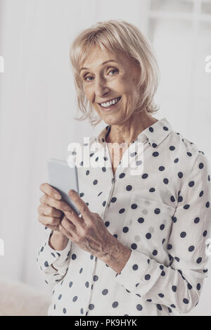 Blue-eyed donna sorridente indossando maculato bianco shirt Foto Stock