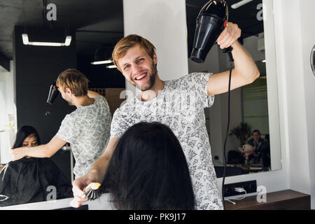 Ritratto di felice parrucchiere tenendo il pettine e phon in salone Foto Stock