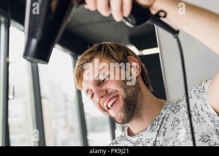 Ritratto di felice parrucchiere tenendo il pettine e phon in salone Foto Stock