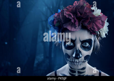 Capelli ricci ragazza con teschio di zucchero Calavera Catrina compongono e red rose fiori naturali con archetto vicino. Giorno dei Morti. Il dia de los Muertos o di Halloween Foto Stock