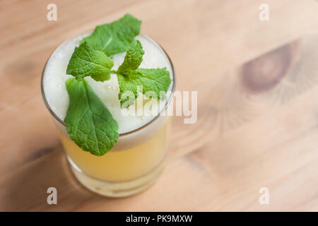 Un fresco cocktail schiumoso o frappè alla menta guarnire su un tavolo di legno o bar. Foto Stock