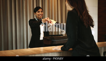 Femmina tenendo guest room key card presso hotel il banco di check-in. Addetta alla ricezione dando la chiave della camera per client in hotel. Foto Stock