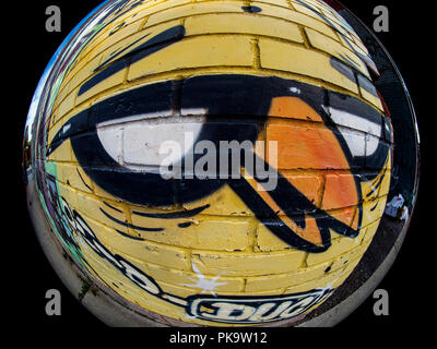 Arte di strada colorato e raffreddare graffiti di un anatra giallo su una presa a parete con un fisheye circolare Foto Stock