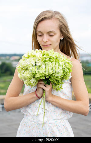 Giovane donna lo sniffing di un mazzo di fiori Foto Stock