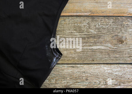 Punto di colore bianco sul vestito ascella e deodorante su uno sfondo di legno. Vista dall'alto. Foto Stock