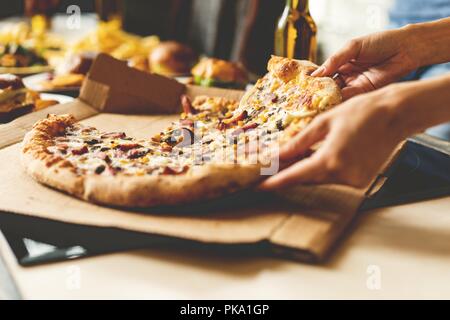 Amici prendendo fette di pizza gustosa dalla piastra, vista ravvicinata. Foto Stock