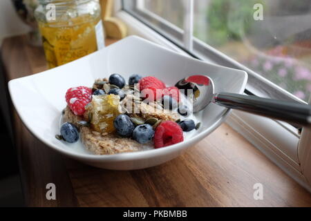 Una sana colazione a base di biscotti di frumento con mirtilli lamponi e miele di acacia e favo di miele Foto Stock