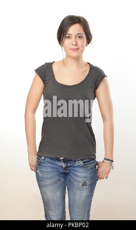 Bella bruna donna in maglietta e jeans mantenendo le mani nelle sue tasche Foto Stock