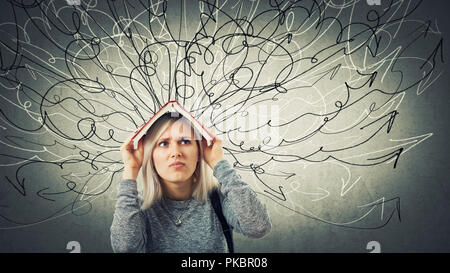 Confuso donna giovane studente tenendo un libro aperto sopra la testa. Triste emozione, infelice sensazione, compito difficile da risolvere. Centinaia di frecce curve e il governo indiano Foto Stock