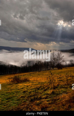 Le nuvole e la nebbia la sella di copertura di montagna come un raggio di sole risplende per un breve istante durante una tempesta di neve. Sella Mountain è una sezione di Ne Foto Stock