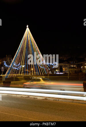 Albero di natale nel parco in Kastoria , Grecia e sentieri di luce di auto Foto Stock