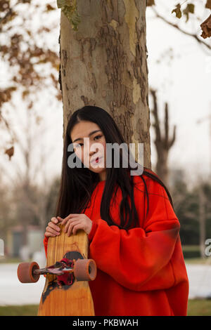 Giovane ragazza di skateboard mantenendo la sua longboard all'esterno. Ritratto, Skateboard Girl Foto Stock