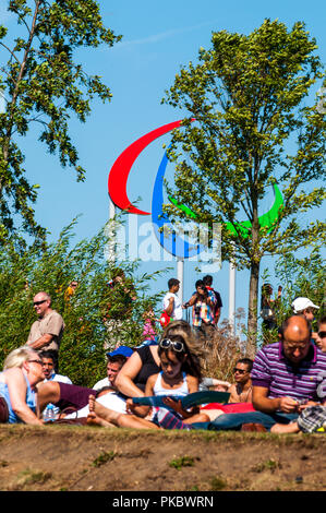 La gente seduta davanti al simbolo Paralimpici presso il London Olympic Park 2012, Inghilterra, Regno Unito Foto Stock