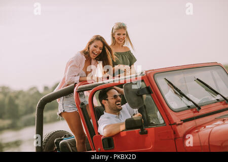Happy amici divertendosi in autovettura convertibile in vacanza da River Foto Stock