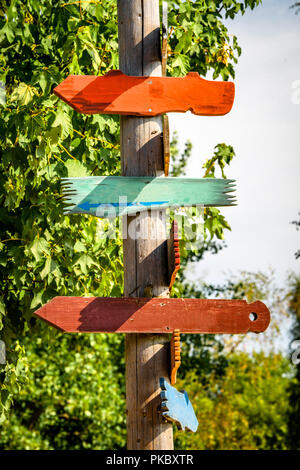 Cartello in legno sagomato come frecce che indicano le direzioni in vari colori Foto Stock