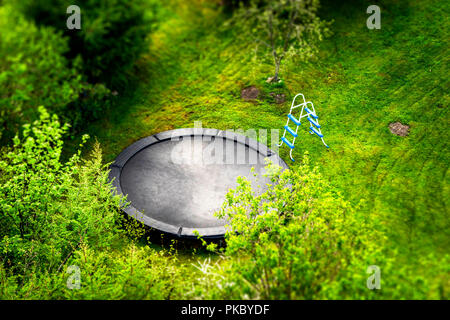 Trampolino di grandi dimensioni in un giardino con una scala circondato da verdi alberi visti da sopra Foto Stock