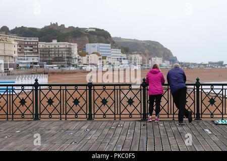 Hastings, East Sussex, Regno Unito. Xii Sep, 2018. Regno Unito: Meteo nuvoloso con una caduta di temperatura e la pioggia prevista per tutta la giornata. Un uomo e una donna stanno sul molo di hastings guardando verso la città vecchia. © Paul Lawrenson 2018, Photo credit: Paolo Lawrenson / Alamy Live News Foto Stock