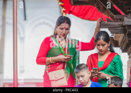 Kathmandu, Nepal - Sep 12,2018:il nepalese donne Indù utilizzando dispositivi mobili a Kathmandu Durbar Square a Kathmandu. Indù donne nepalesi fast e desiderio di una vita prospera del loro coniuge e la famiglia in questo festival.Il festival per le donne, comprendono danze, canti, insieme con gli amici, indossando il rosso, verde o arancione, vestiti, condivisione di cibi festosa Credito: Nabaraj Regmi/Alamy Live News Foto Stock