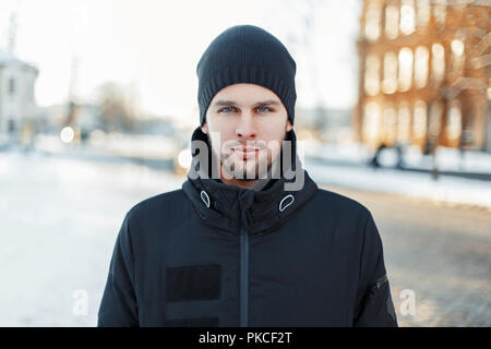 Uomo bello in un caldo abbigliamento invernale a piedi in città al tramonto Foto Stock