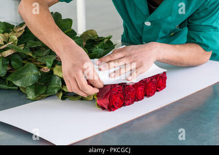 L'uomo confezioni i fiori con un foglio di carta, la preparazione per il trasporto Foto Stock