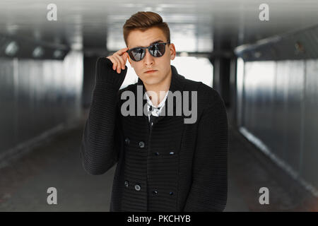 Giovane uomo regola i suoi occhiali da sole Foto Stock