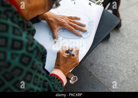 Donna anziana in bicchieri è il disegno su carta. Mano che tiene una matita Foto Stock
